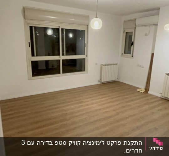 חדר עם רצפת פרקט, חלון ותאורה תלויה